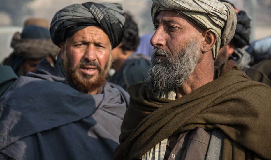 Zwei Männer in Winterkleidung bei einer Feuerholzverteilung in Kabul.