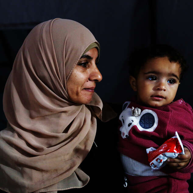 Eine Frau mit einem Kleinkind auf dem Arm, Gaza