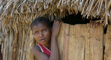 Eine Frau schaut aus ihrer Hütte in Madagaskar.