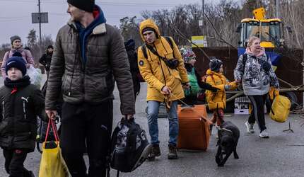 Jetzt für die Ukraine spenden. Mehrere Menschen mit Koffern und Taschen gehen auf die Kamera zu.
