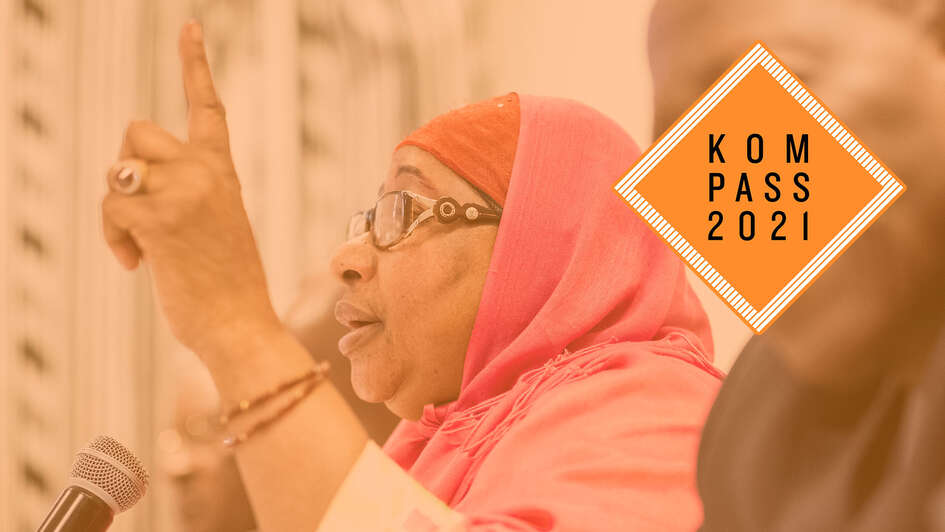 Präsentation des Welthunger-Index. Eine Frau hebt ihre Hand, vor ihr steht ein Mikrofon. Oben rechts ist das Kompass 2021 Logo.