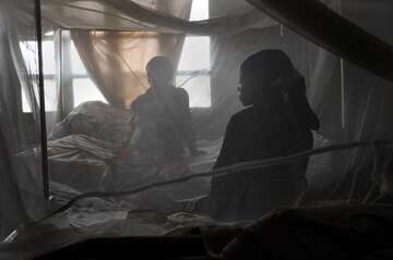 Frauen auf der Geburtenstation im Kongo Zwei Frauen sitzen auf einem Bett, davor ein Netz