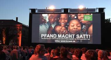 "Pfand macht satt" beim Open Air Kino 2017 Publikum und Leinwand mit Werbung zu der Aktion "Pfand macht satt"
