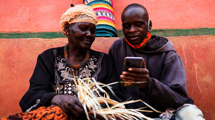 2021-agrishare-fatuma-oluke-mit-smartphone.jpg Zwei Landwirte in Uganda verwendet das Smartphone um Landarbeiter zu finden, 2021.