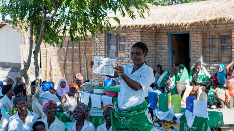 2019-community-health-club-malawi-lycka-welthungerhilfe-2.jpg Eine Frau hält ein Plakat in der Hand und erklärt.