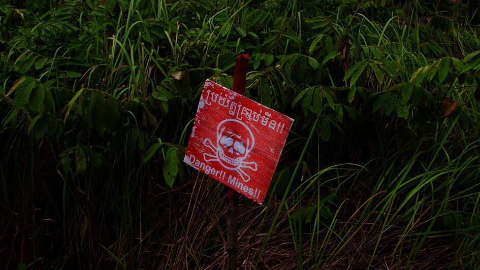 Ein rotes Schild mit einem Totenkopf darauf warnt vor Minen