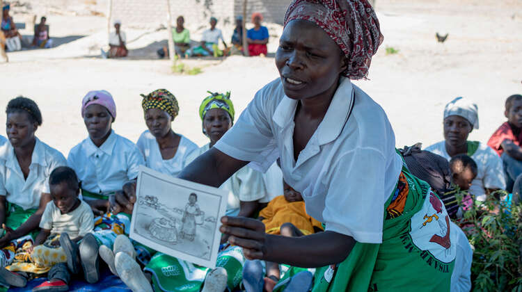 2019-community-health-club-malawi-lycka-welthungerhilfe.jpg Eine Frau hält ein Plakat in der Hand und erklärt.