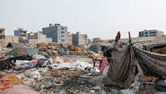 2020-coronavirus-freu-slum-delhi-klimawandel-indien-c-florian-lang.jpg Eine Frau hebt Töpfe vom Boden auf. Um sie heraum sieht man Zeltplanen, Unrat und Müll.