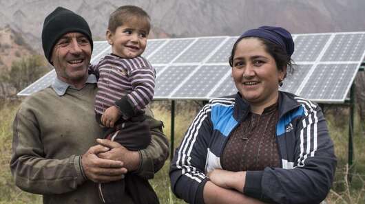 Eine Familie vor ihrer Solaranlage in Tadschikistan.