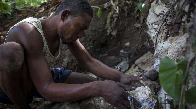 Boden sichern Ein Kleinbauer in Haiti untersucht einen erodierten Erdrutsch