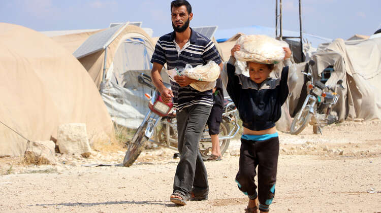 2019-fluechtlinge-idlib-brotverteilung-syrien_C_HIHFAD-hires.jpg Ein Mann und ein Kind tragen Beutel mit Fladenbrot