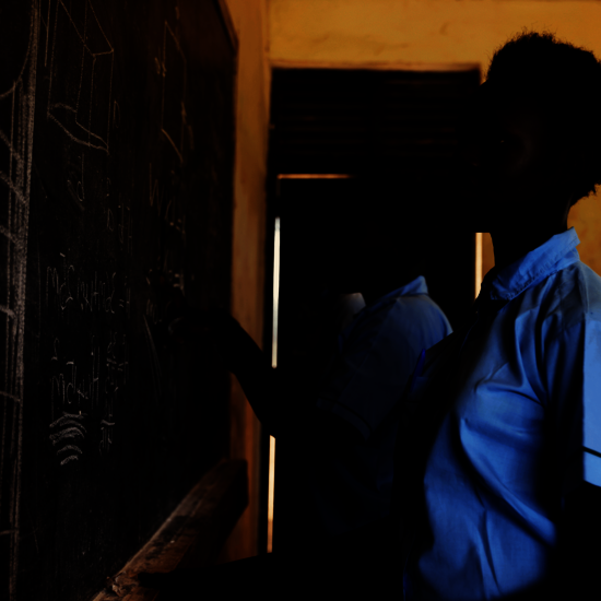 Bild aus einem Projekt im Südsudan mit Schulspeisungen, ein Mädchen steht an einer Schultafel.