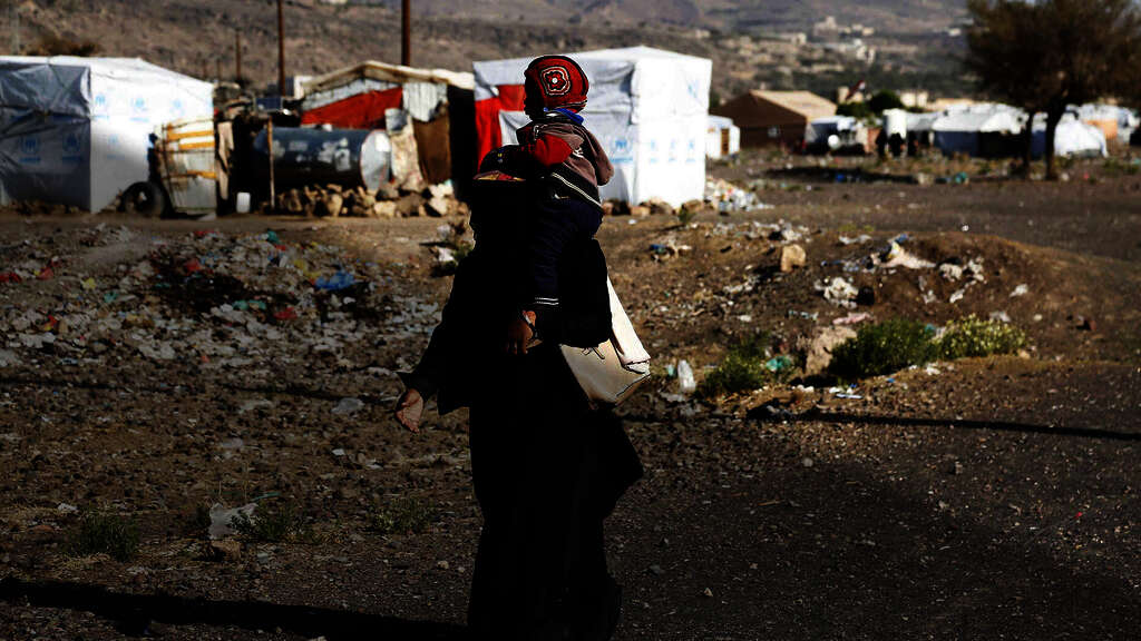 Nothilfe in Jemen. Eine Mutter trägt ihr Kind durch das Dharawan Flüchtlingscamp in Sanaa.