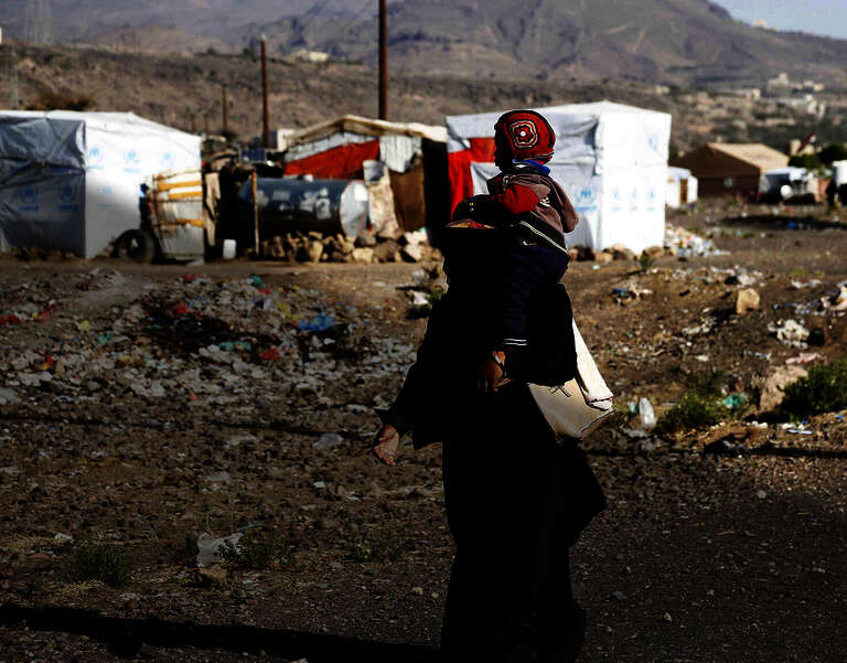 Nothilfe in Jemen. Eine Mutter trägt ihr Kind durch das Dharawan Flüchtlingscamp in Sanaa.